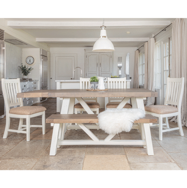 modern farmhouse dining table with left side extended. surrounded by 4 chairs on sides and back and bench in the foreground- all in a white kitchen setting