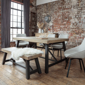 Urban dining table set with dining bench and fabric chairs placed in a room with industrial style decor