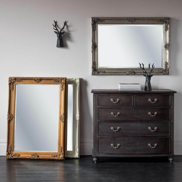 Ornate Rectangle Mirror hanging landscape above a chest of drawers with two standing portrait on the floor