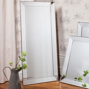 Bevelled Leaner Mirror leant against a wallpaper wall with smaller mirrors and a decorative jug with flowers next to it