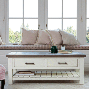 Modern farmhouse rustic coffee table with drawers in front of window seat with 4 pale cushions