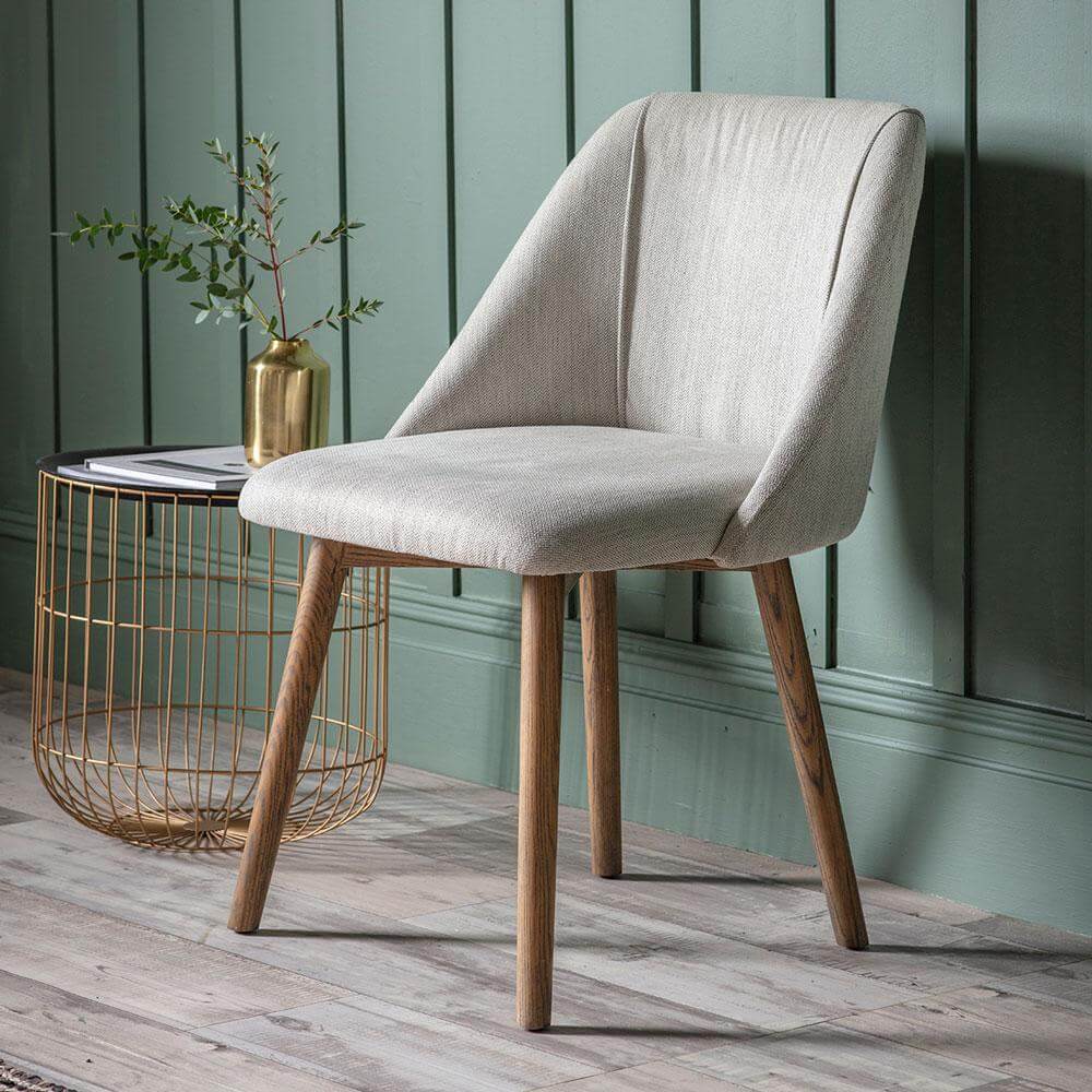 The Ash Dining Chair in Neutral placed against a light green wall