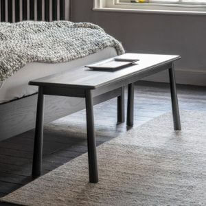 The Bergen Dining Bench in Black placed at the end of a bed