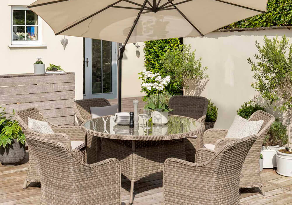 2021 Kettler Charlbury 6 Seat Garden Dining Set With Round Table In a garden under a tilted parasol