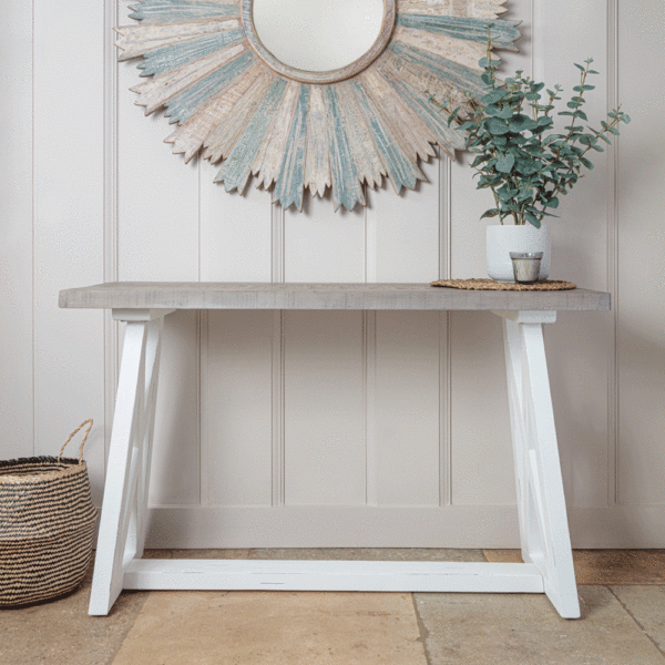 white and grey console table against wall under large circular gold mirror.