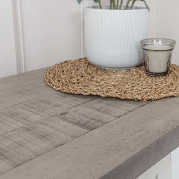 top close up of white and grey console table surface showing table mat, candle and plant