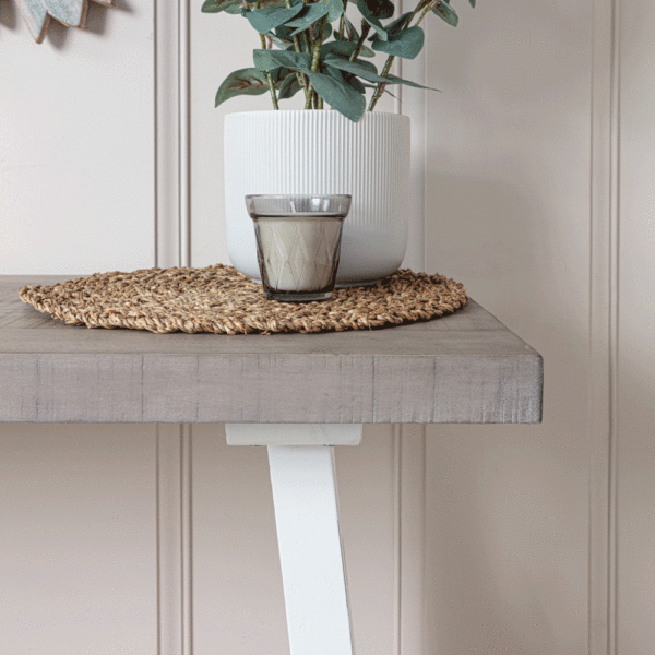 close up of right side surface of white and grey console table with plant and candle on top