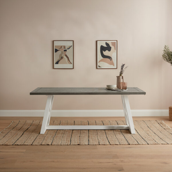 pine dining table with white base and grey worktop on wood floor with rug and hung art on wall behind