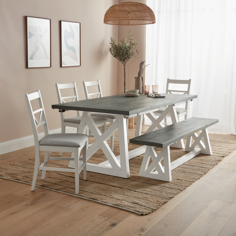 White and Grey Extendable Dining table set with four white base and grey fabric dining chairs with matching dining bench, on rug on wood floor in well lit room