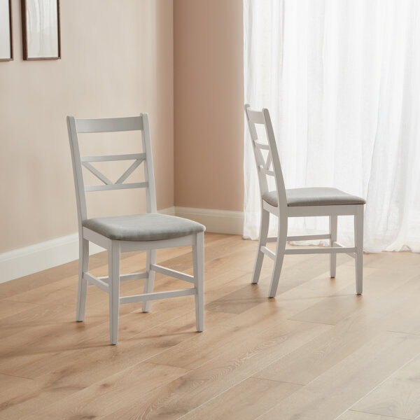 rustic dining chairs with white bases and grey seat pads stood on wooden floor in room with dusky colours