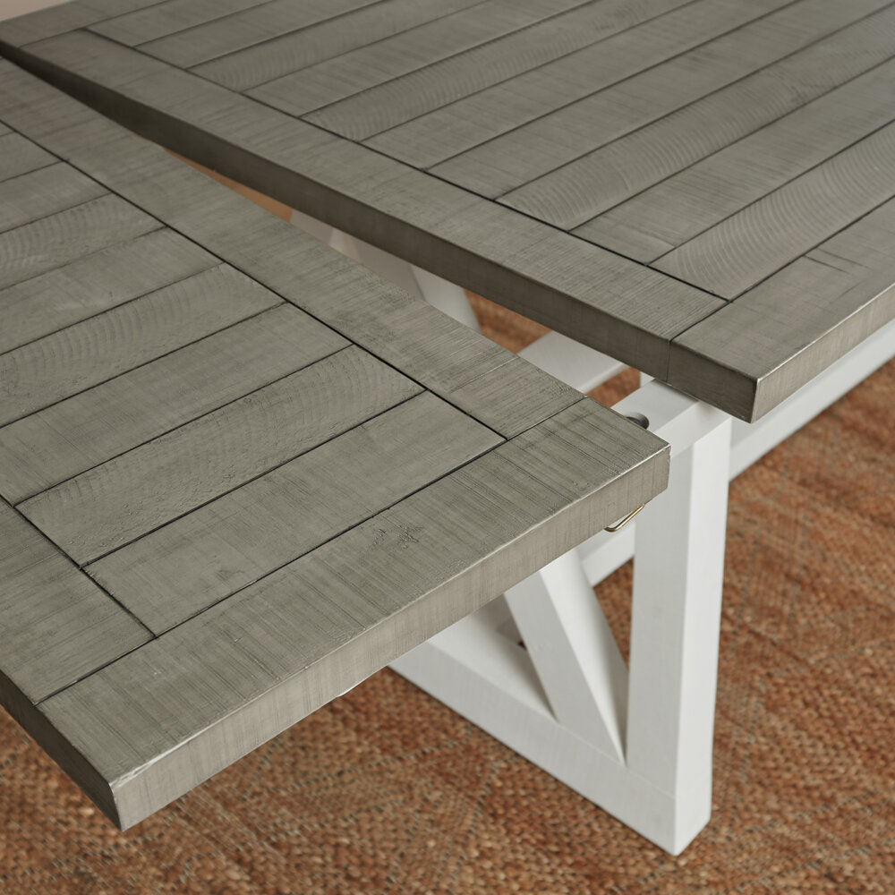 angled shot showing a grey tabletop of a white and grey extendable dining table with extension leaf being inserted, not fully inserted