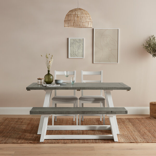 White and Grey extendable dining table set placed in a light room with vase on the table and rattan lampshade hung overhead