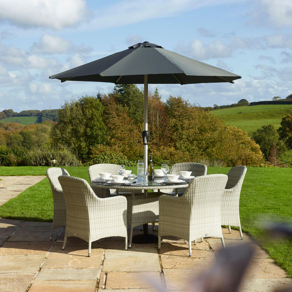 2021 Bramblecrest Tetbury 6-Seat Round Garden Dining Table Set With Parasol On a garden patio