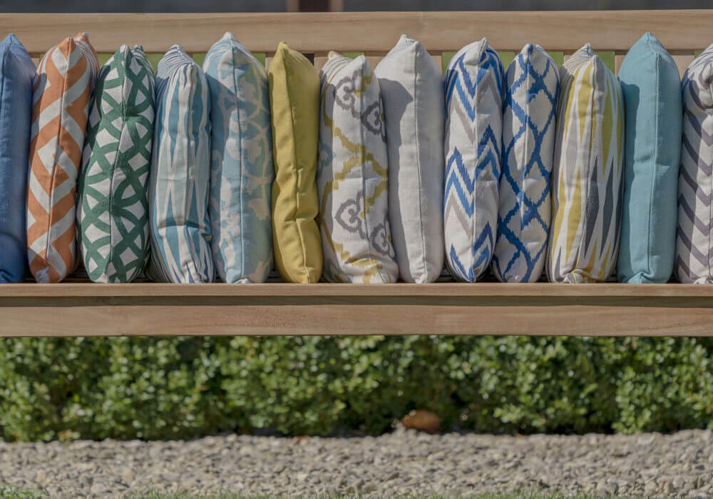 Close up of variety of bramblecrest square scatter cushions on outdoor bench