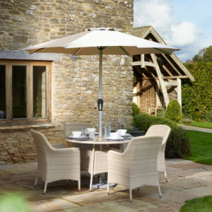 2021 Bramblecrest Tetbury 4-Seat Dining Table Set With Parasol In a Garden Setting