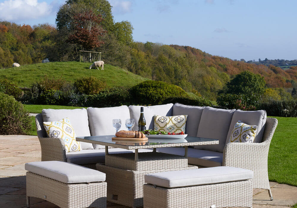 2021 Bramblecrest Tetbury Garden Sofa Set With Rectangle Adjustable Table on a patio in front of a field with rolling hills