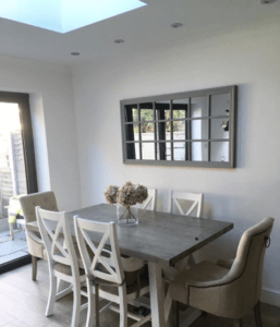 white and grey dining table set in home next to white wall with window mirror