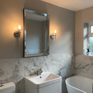 white marble bathroom with silver mirror and wall lights over sink