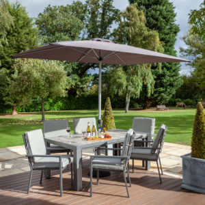 2020 Hartman Titan 6 Seat Rectangular Dining Set with Tuscan Ceramic Table and 3m Solar Parasol - Pewter/Seal on deck infront of large lawn