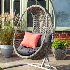 single hanging cocoon chair on deck outside conservatory next to potted plants