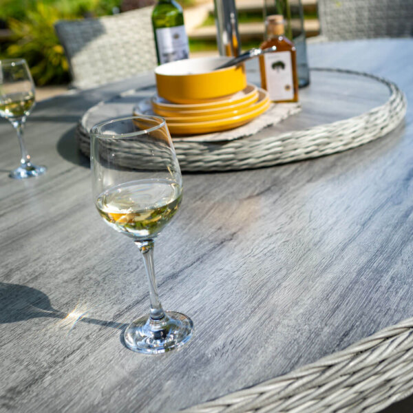 close up of elliptical dining set table top with lazy susan in background and wine glass in foreground
