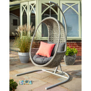 full image of single hanging cocoon chair on deck outside conservatory next to potted plants