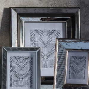 Large mirror photo frame amongst smaller photo frames with beige textured wall behind