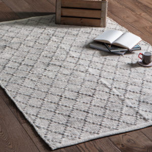 Nordhem Rug Natural indoors with open book and mug placed on top