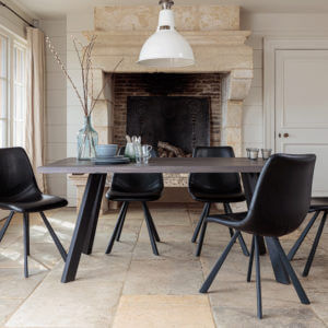 Valencia Smokey Dark Oak Dining Set With 5 X Dali Black Leather Dining Chairs in front of large stone fireplace