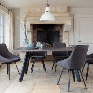 Valencia Smokey Dark Oak Dining Set With 5 X Gaudi Dark Grey Dining Chairs in front of large stone fireplace