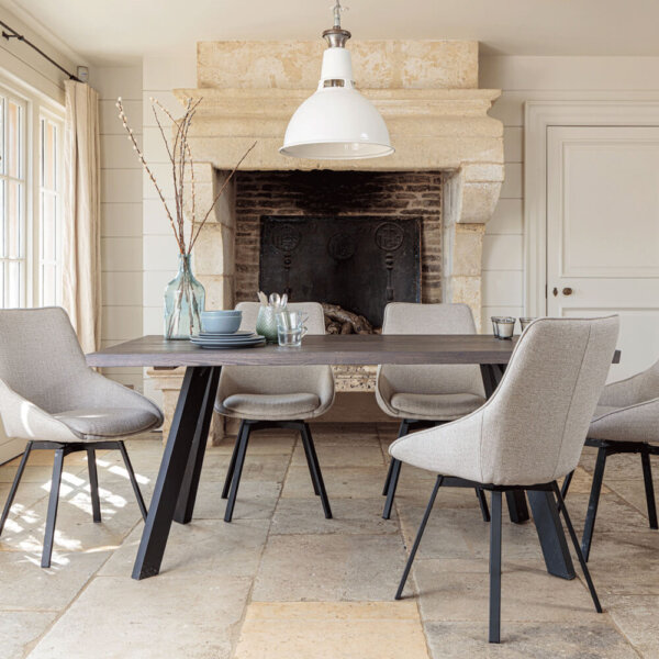 Valencia Smokey Oak Dining Set With 5 X Gaudi Light Grey Dining Chairs in front of large stone fireplace