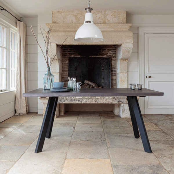 Valencia Smokey Dark Oak Dining Table on stone floor in front of place stone fireplace