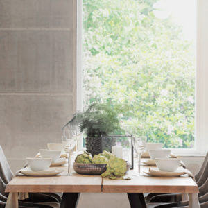 Valencia Light Oak Dining Table fully set with chairs and dinnerware-set next to large window