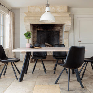 Valencia Light Oak Dining Set With 5 X Dali Black Leather Chairs in front of large stone fire place