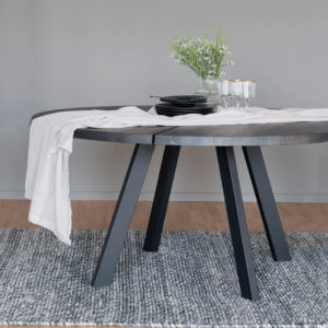 Valencia Smokey Oak Round Dining Table with white table runner, vase and black crockery on top