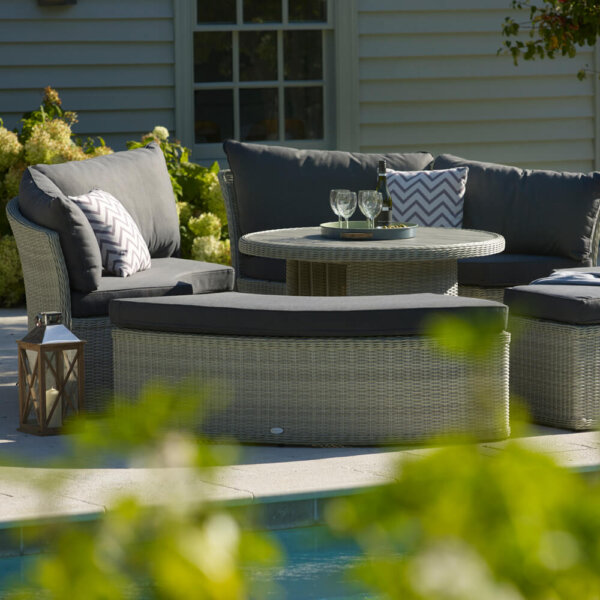 Side view Of The Bramblecrest Monterey Circular Garden Daybed In Front Of A Pool With Plants In The Foreground