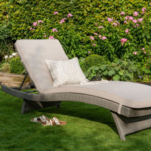 Kettler Charlbury Garden Lounger_in_garden with cream cushion, sunglasses and a book on it in a pleasant garden setting