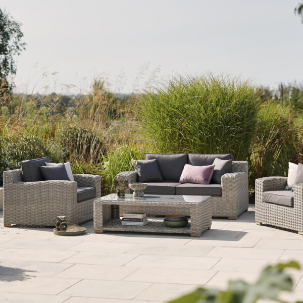 garden_furniture_with_grey_cushions_on_paving_with_foliage_background