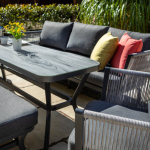 Various_grey_metallic_garden_furniture_with_yellow_and_red_cushions_in_sunshine_drenched_garden