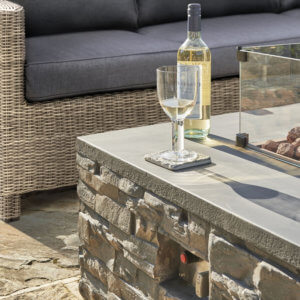 Kettler Stone Fire Pit Coffee Table 132 x 85cm with Glass Shield and Cover on a garden patio next to an outdoor sofa