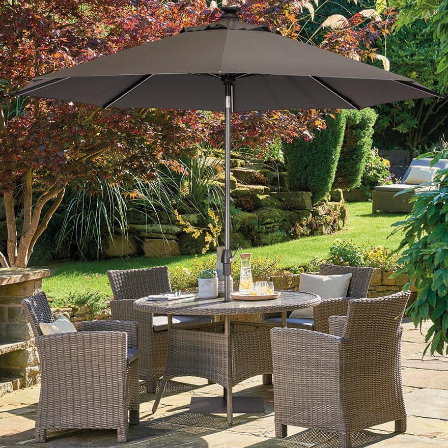 Kettler 3m Wind Up Auto Tilt Parasol with LED Solar Lights placed in round outdoor dining table on garden patio