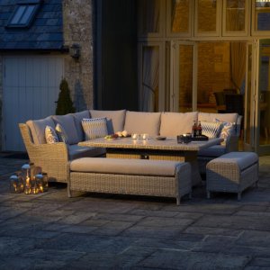 Bramblecrest Chedworth Garden Sofa Set with Rectangle Fire Pit Dining Table & 2 Benches - Sandstone on outdoor patio at night with lite candles
