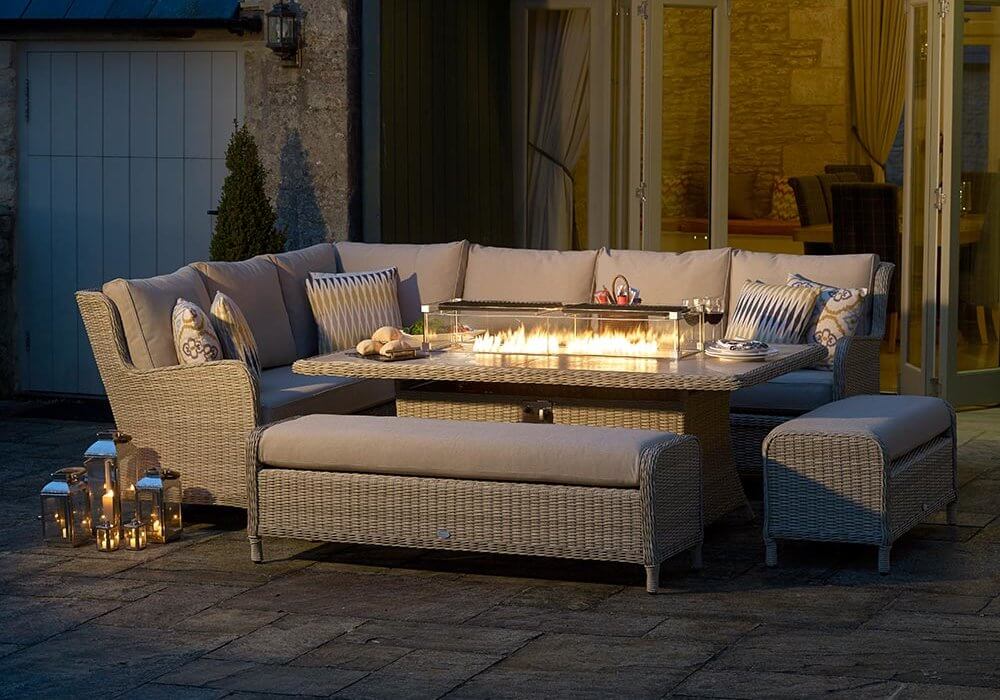 Bramblecrest Chedworth Rectangle Firepit Dining Table Set on patio with firepit lit up