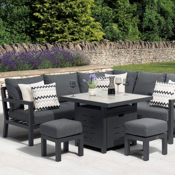 left view of Bramblecrest La Rochelle Mini Corner Sofa Set With Fire Pit Ceramic Table with 2 x stools - Anthracite/Dark Grey on white patio in front of walled garden