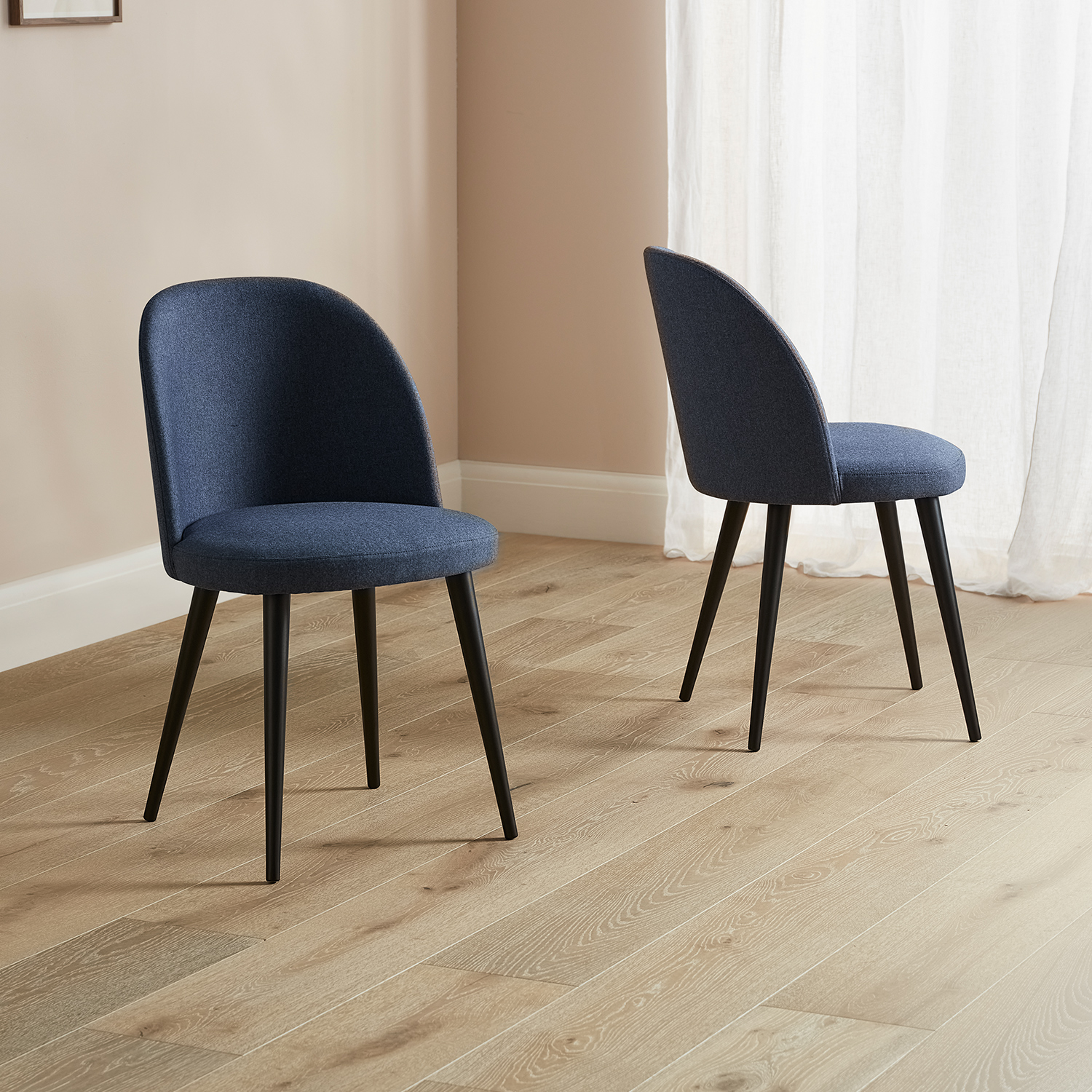 Burnham dining chairs in navy blue with black legs placed on a wooden floor