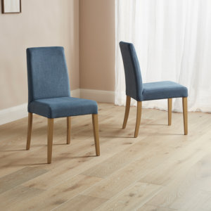 Selwood dining chairs in denim with natural wood legs placed on a wooden floor