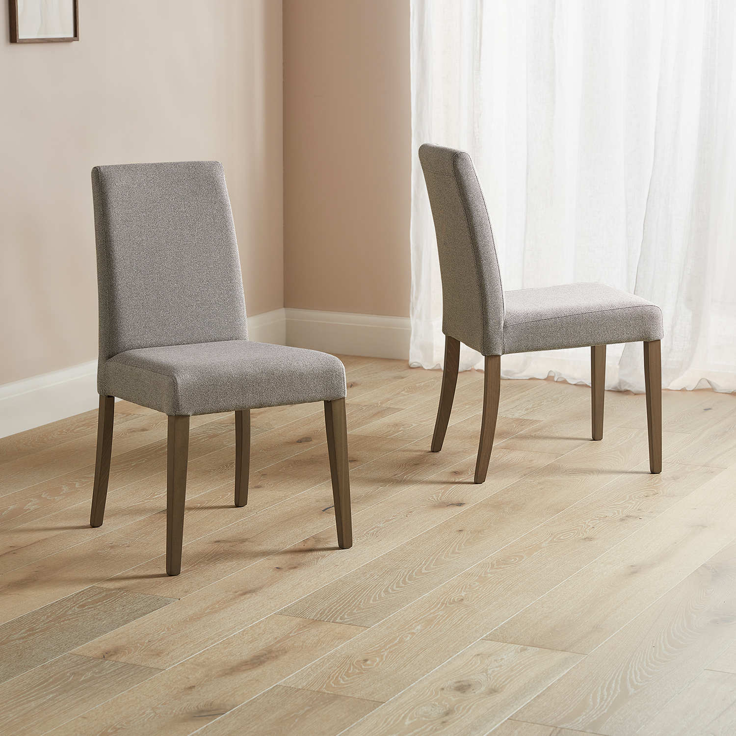 pair of Selwood dining chairs in mushroom with dark wood legs placed on a wooden floor