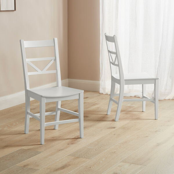 white dining chairs placed on a wooden floor in dusky colour room