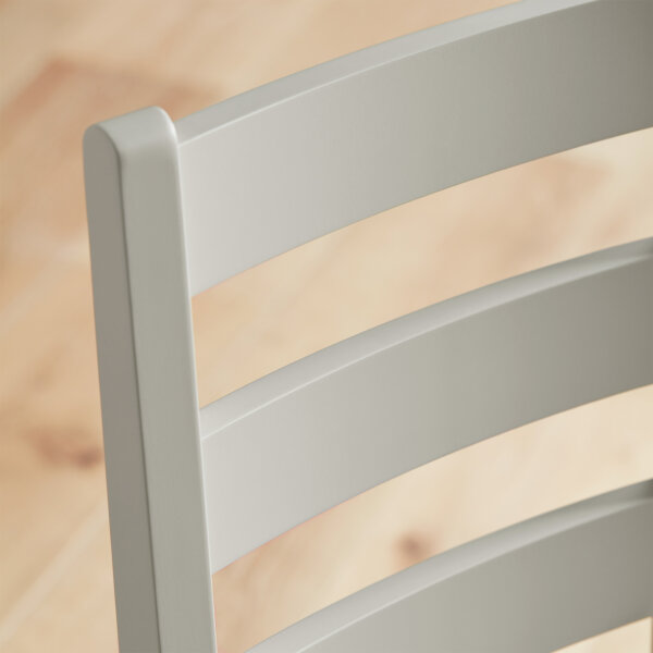 white dining chairs with strut back design and seat pads stood on wooden flooring in dusky shaded room